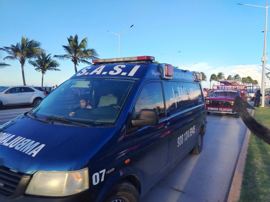 Ambulancia azul de urgencias avanzadas SASI circulando junto a la costa, con palmeras al fondo